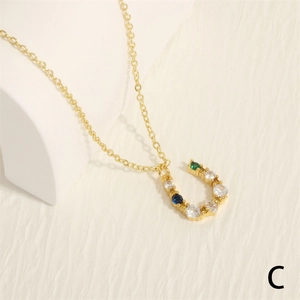 Macro detail of U-shaped gold necklace pendant with colorful zircon stones on stones