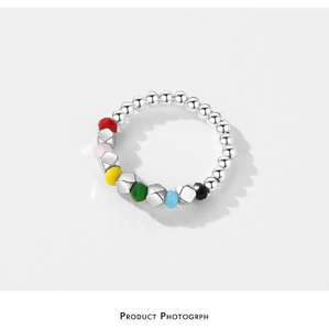 Detailed macro shot of colorful faceted beads and silver geometric rings on a modern band