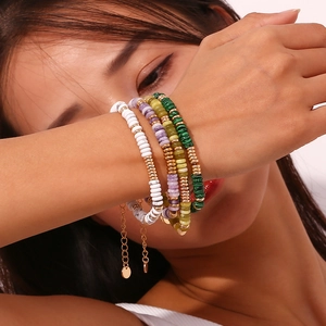 Nahaufnahme von geschichteten Perlenarmbändern mit Natursteinen und Goldperlen am Handgelenk