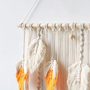 Detail of hand-woven macrame wall hanging with orange gradient feather leaf tassels