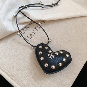 Detailed view of a black heart leather pendant with silver studs and cross emblem