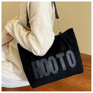 Detail of black tote bag with HOOTO lettering and metal chain leather shoulder strap
