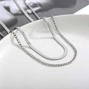 Detail of silver double-layered necklace featuring flat snake chain and Cuban link design