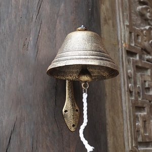 Large vintage cast iron doorbell on dark wood post with rustic bronze finish and rope