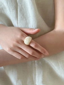 Detailed view of wide marble resin ring in cream yellow on model with linen background