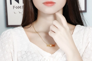 Detailed close-up of golden MOM heart pendant necklace worn by a model