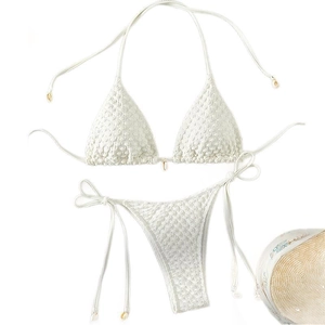 White shell-accented bikini set with textured fabric laid flat next to a straw hat