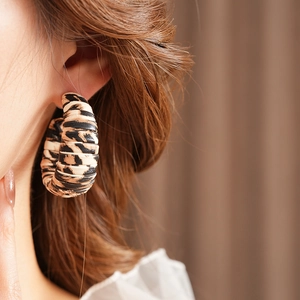 Close-up of leopard print leather C-shaped hoop earrings worn by a model