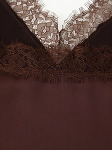 Close-up of deep brown silk satin fabric with delicate eyelash lace trim detail