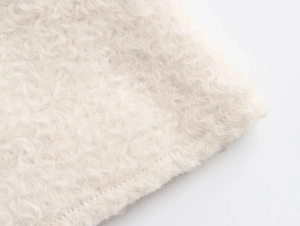 Detailed close-up of cream white sherpa fleece fabric texture with neat stitching