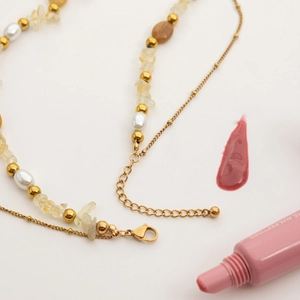 Detail of 18K gold stainless steel necklace with sun pendant, pearls and yellow citrine