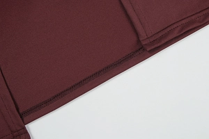 Detailed close-up of high-density overlock stitching on burgundy knit fabric hem