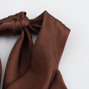 Macro detail of dark brown satin dress featuring a sophisticated knot design and fabric texture