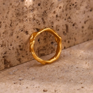 Macro shot of gold plated stainless steel ring with irregular wavy melting surface texture