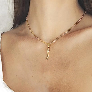 Detail of gold cornicello chili pendant with flat metal chain on model neckline