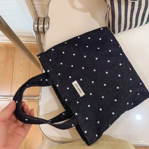 Detailed macro view of denim tote bag with white polka dots and simple wish label