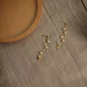 Detail of elegant gold long tassel earrings featuring multiple white freshwater pearls
