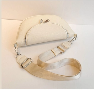 Detail of off-white crescent crossbody bag with lychee texture and dual silver zippers
