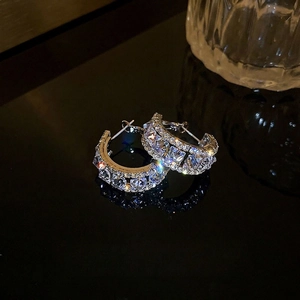 Sparkling silver C-shaped hoop earrings featuring multiple rows of cubic zirconia stones