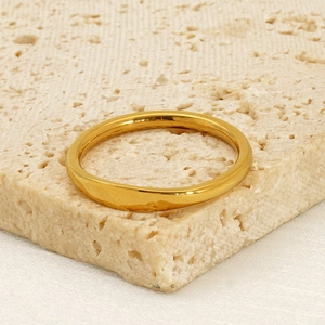 Minimalist 18K gold plated stainless steel band ring on a beige travertine stone