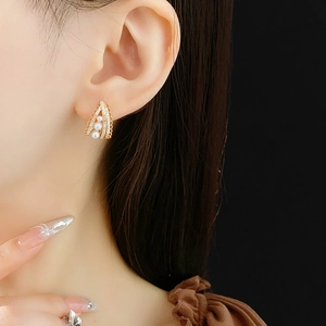 Detail of vintage gold pearl earrings with zircon lace triangle design on model