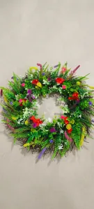 Close-up of colorful artificial flower wreath with green leaves on dry branch base