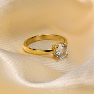 Close-up of a four-prong set round white zircon on a polished gold stainless steel ring