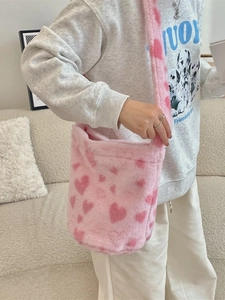 Pink plush bucket bag with heart patterns and soft shoulder strap in a stylish crossbody view