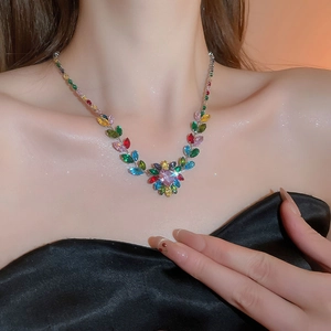 Close-up of a necklace featuring colorful leaf-shaped cubic zirconia worn by a model