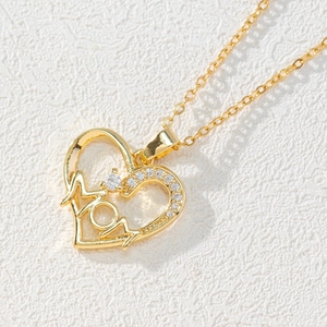 Detail shot of a gold heart-shaped MOM pendant necklace with zircon stones on white background