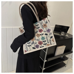Detail view of colorful floral embroidery on high-capacity cream canvas tote bag