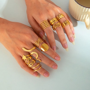Detail of stacked snake-shaped and star-patterned 18k gold-plated stainless steel rings