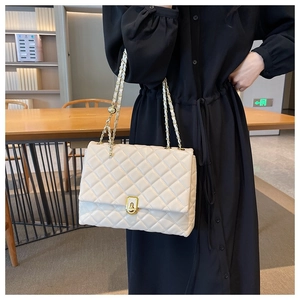 White quilted crossbody bag with gold chain strap shown on model in modern interior