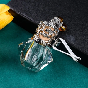 Detailed close-up of a faceted glass car perfume diffuser bottle with silver carved lid