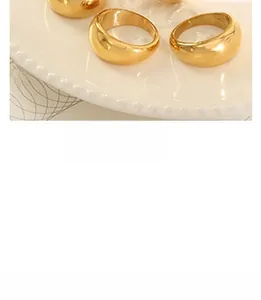 Close-up of golden dome ring with polished metallic finish on white ceramic plate