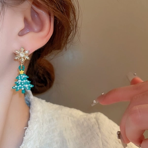 Close-up of model wearing Christmas tree earrings with snowflakes and pearls
