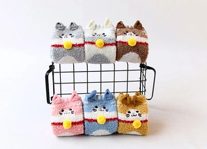Close-up of fluffy coral fleece socks with cute cat ears and 3D bell collar designs