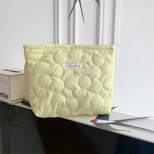 Detail of light yellow flower quilted makeup bag with zipper and logo label