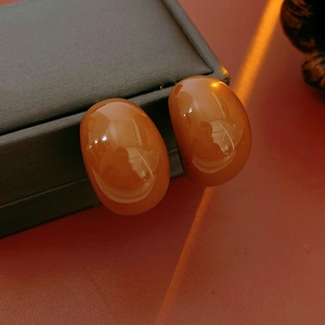 Macro detail of amber resin oval drop earrings on elegant jewelry box surface