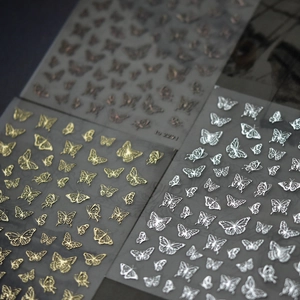 Detailed macro view of gold, silver and bronze 3D butterfly nail art stickers in various poses