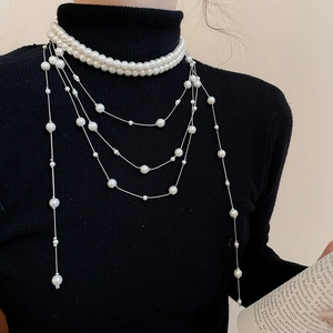 Detail of elegant multi-layer pearl fringe necklace worn on a black sweater