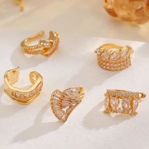 Nahaufnahme von vergoldeten Ohrklemmen mit Zirkonia auf einer weißen Steinfläche