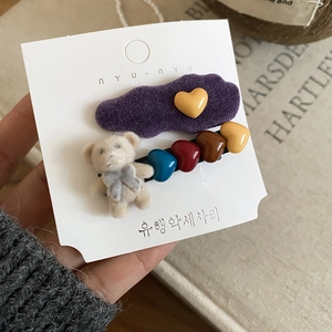Detailed view of flocked purple heart clip and beige teddy bear hair accessory set