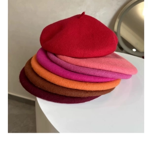 Stack of thick wool berets in vibrant colors like red, pink, orange, and purple