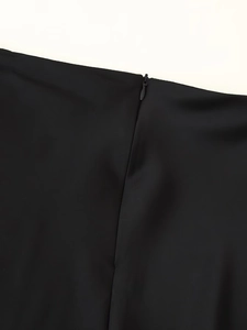 Detail eines unsichtbaren Reißverschlusses an glattem schwarzem Satin-Top und Rock