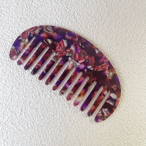 Top view of portable acetate crescent comb with vintage purple floral pattern detail