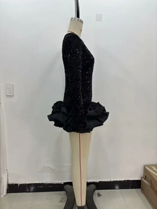 Détail d'une robe noire à paillettes avec ourlet à volants et manches longues ajustées