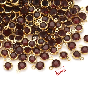 Close-up of 6mm gold stainless steel pendants with dark red crystal birthstone charms