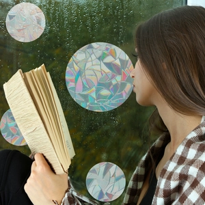 Close-up of circular rainbow window film on wet glass with prismatic light effect