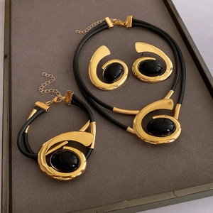 Detailed set of gold metal oval spiral necklace and earrings on a grey tray
